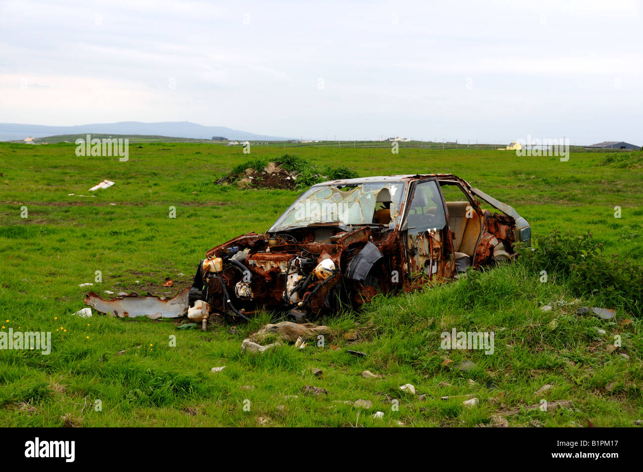 Ein verlassenes Auto rostet im grünen Feld offen. County Clare, Irland. Stockfoto