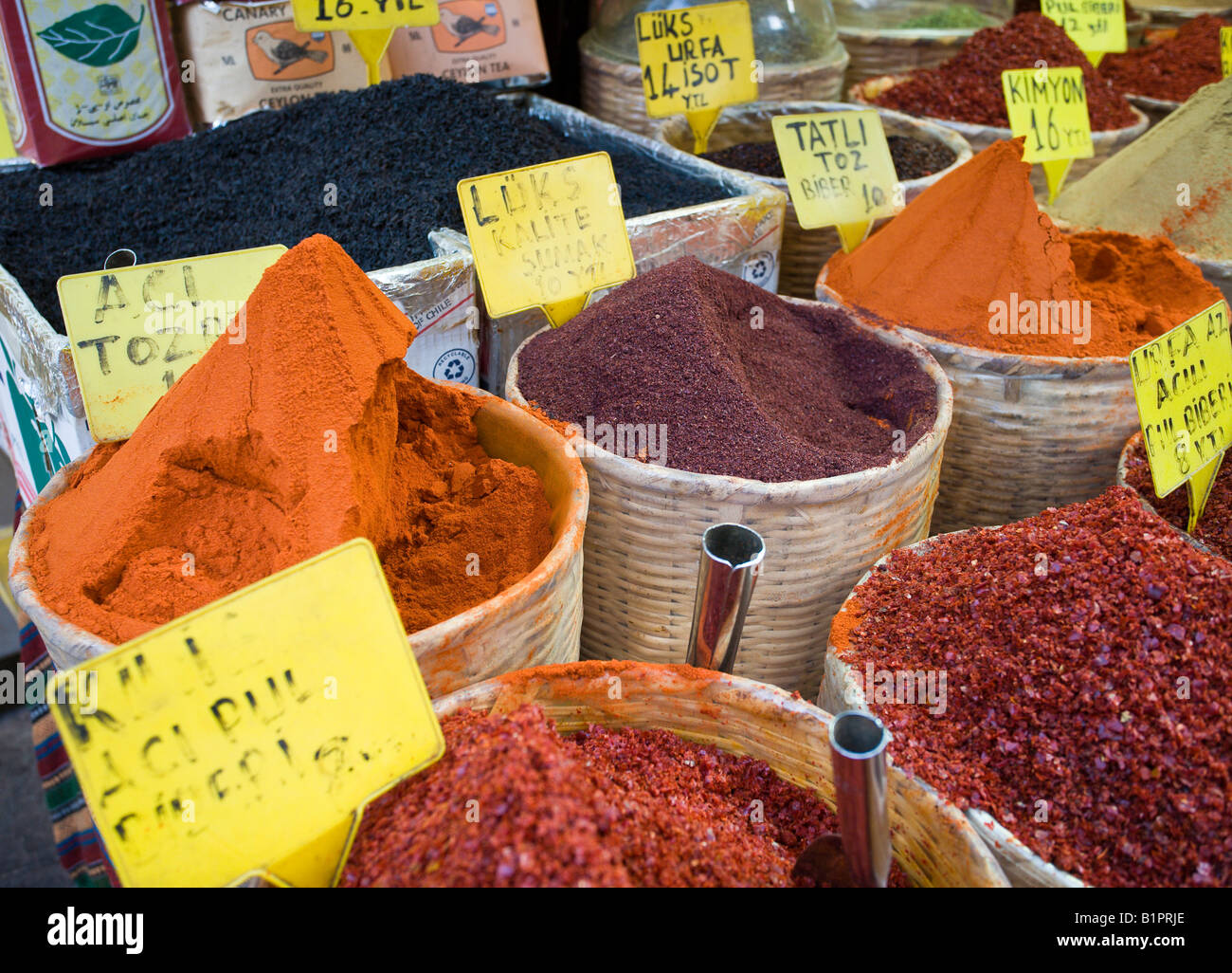 Körbe von Gewürzen, die horizontale bunte orange und rote Gewürze in weißen geflochtenen Körben hoch aufgetürmt locken Käufer Stockfoto