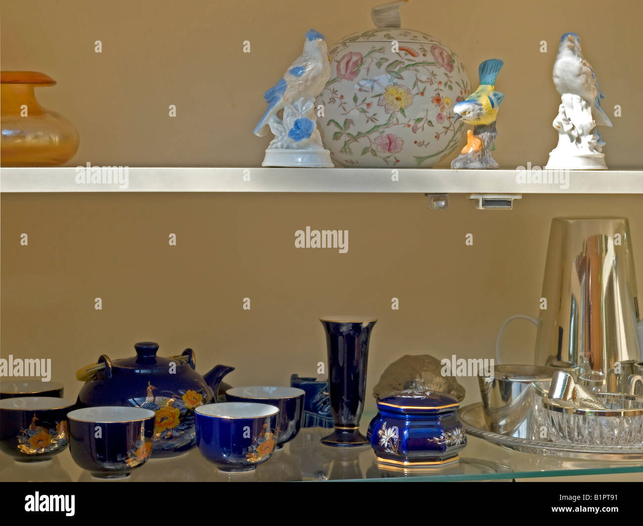 Figuren der Vögel von China mit Schale in blau florales Design Teeservice und Tee-Set aus Kristallglas in einem Schrank Kitsch gemacht Stockfoto