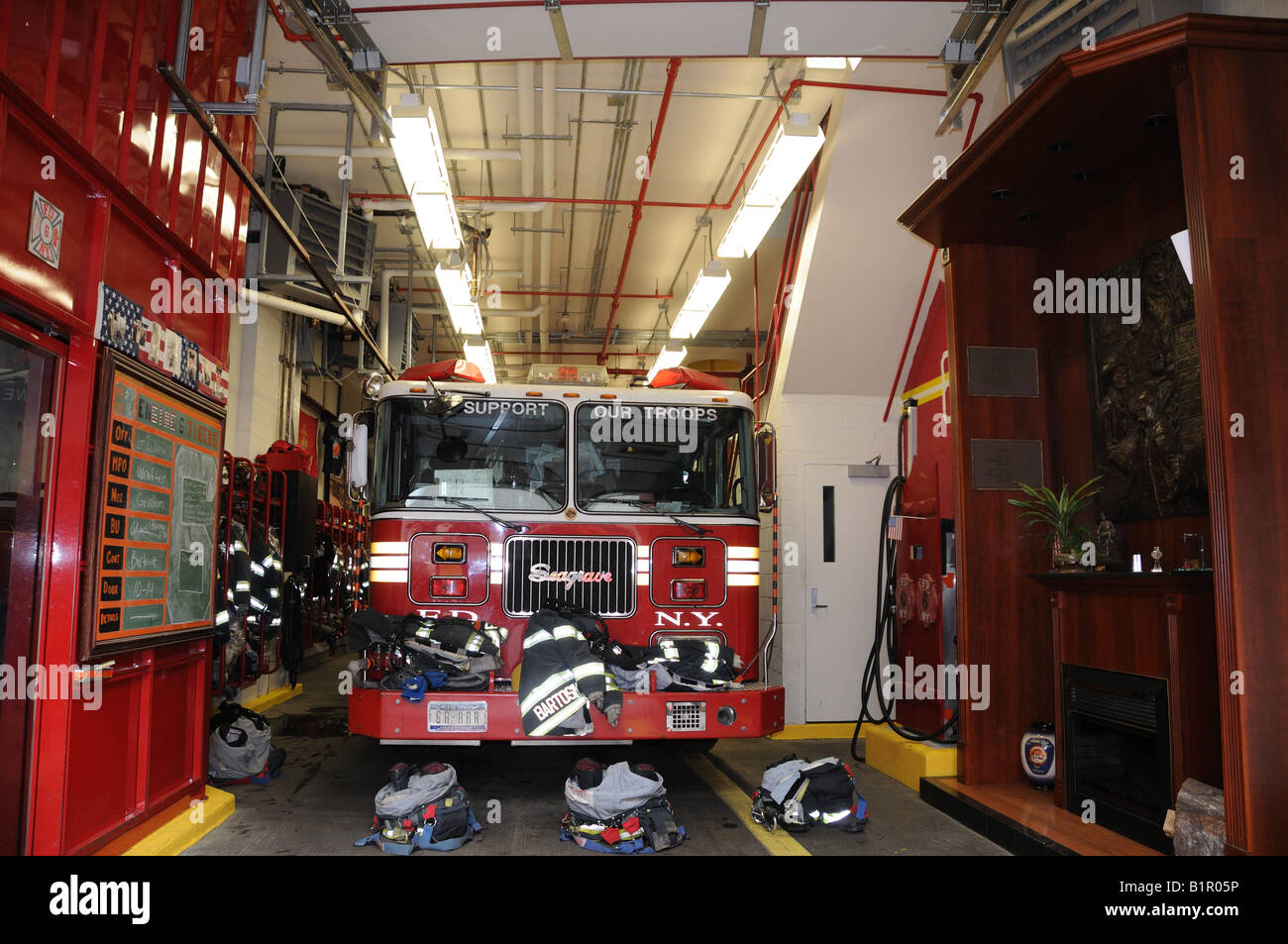 Das Innere einer Feuerwache in Manhattan. Die Männer haben ihre Ausrüstung vor dem Feuerwehrauto einsatzbereit. Stockfoto