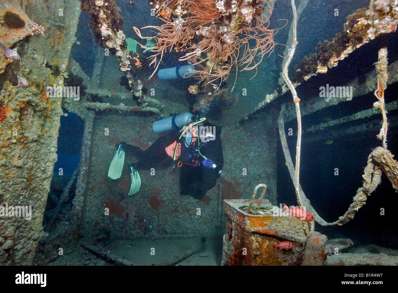 Eine Taucher spiegelt sich eingeschlossene Luft an der Decke, wie sie ihre Fackel in das Rote Meer WW2 SS Thistlegorm Schiffswrack glänzt. Stockfoto