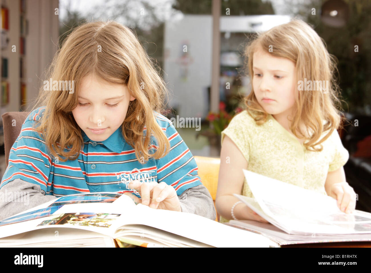 Mädchen, 8 Jahre alt, und junge, 10 Jahre alt, betrachtet man Fotoalben Stockfoto