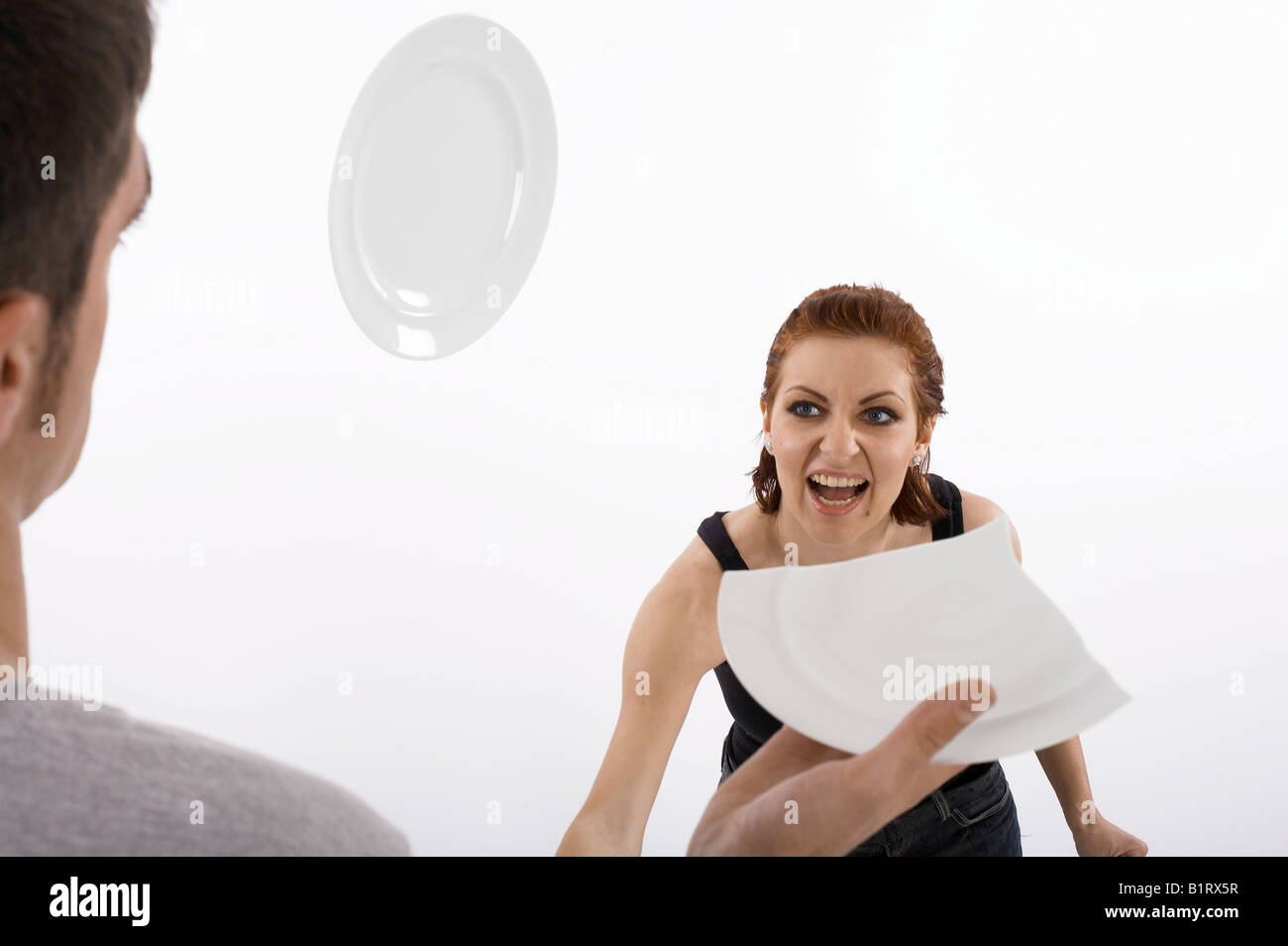 Frau eines Mannes Kopf während eines Streits einen Teller bewerfen Stockfoto