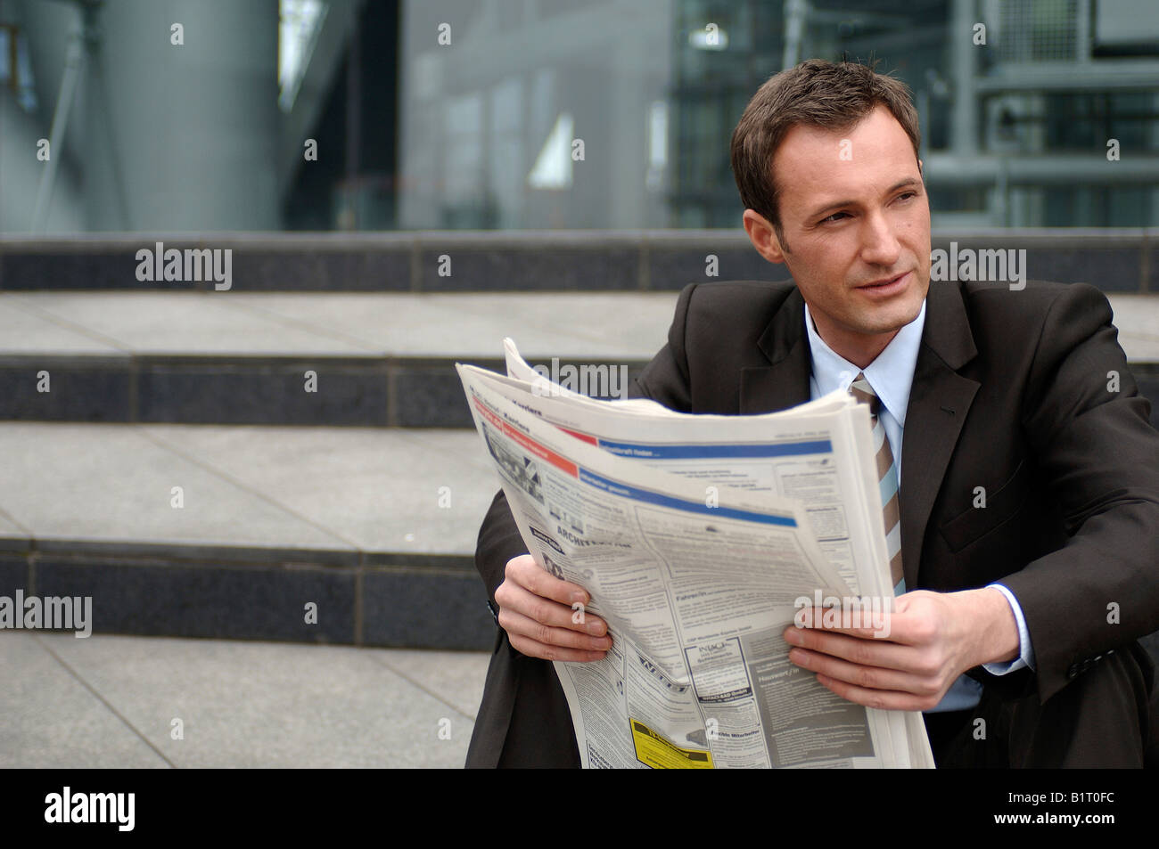 31-Year-Old Geschäftsmann trägt einen Anzug mit Zeitung Stockfoto