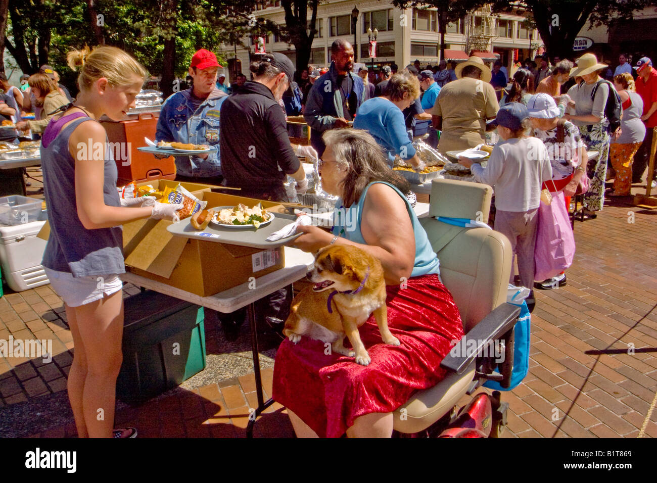 Tragen ihren Hund auf dem Schoß schließt sich eine Rollstuhl gebundene Frau andere Obdachlose für einen freien Sonntag Mahlzeit in Portland, Oregon Stockfoto