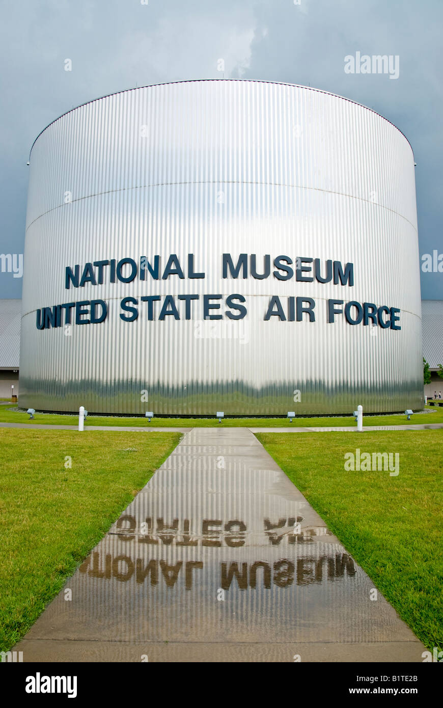 Eingang des National Museum of the United States Air Force Dayton Ohio // DAYTON, Ohio, Vereinigte Staaten — der Haupteingang des National Museum of the United States Air Force auf der Wright-Patterson Air Force Base in der Nähe von Dayton, Ohio. Der Name des Museums spiegelt sich nach einem Regensturm in einer Pfütze wider, die ein Spiegelbild der Fassade und Beschilderung des Gebäudes erzeugt. Stockfoto