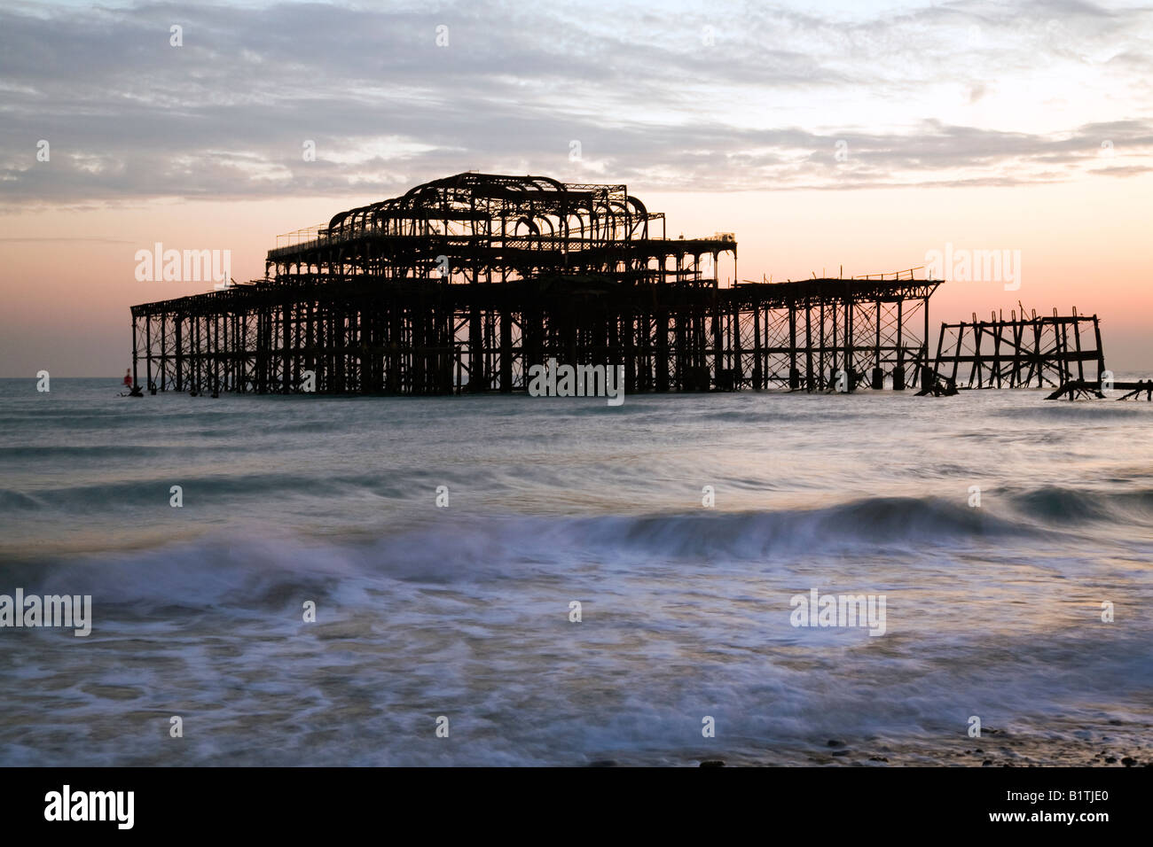 Die Sonne geht über Brightons West Pier bei Ebbe Stockfoto