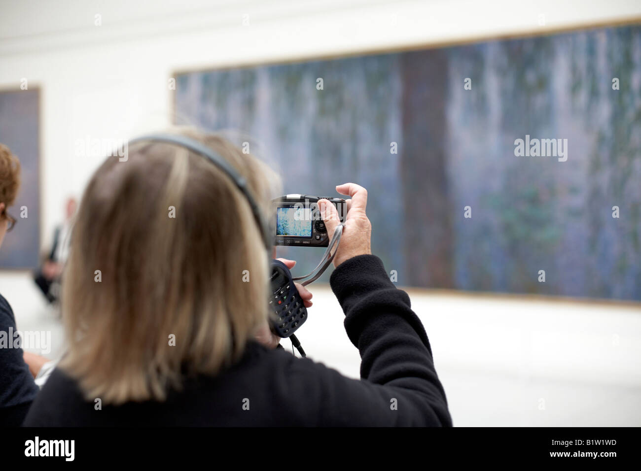 Frau trägt Kopfhörer digital fotografieren in Galerie, Orangerie, Paris Stockfoto