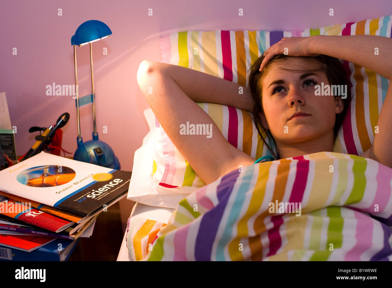 Teenager-Mädchen im Bett mit GCSE Überarbeitung Bücher rund um ihr schauen ängstlich Stockfoto