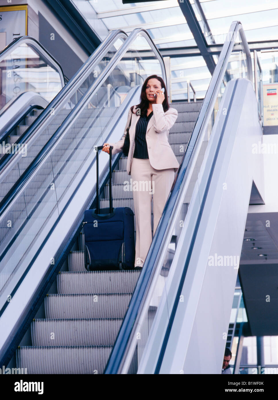 Frau auf dem Handy bei Rolltreppe Stockfoto