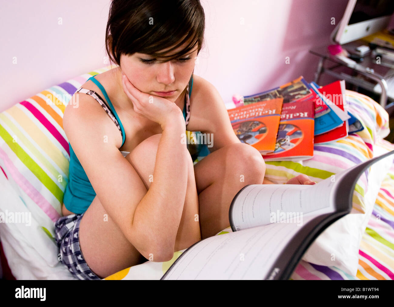 Teenager-Mädchen im Bett mit GCSE Überarbeitung Bücher rund um ihr schauen ängstlich Stockfoto