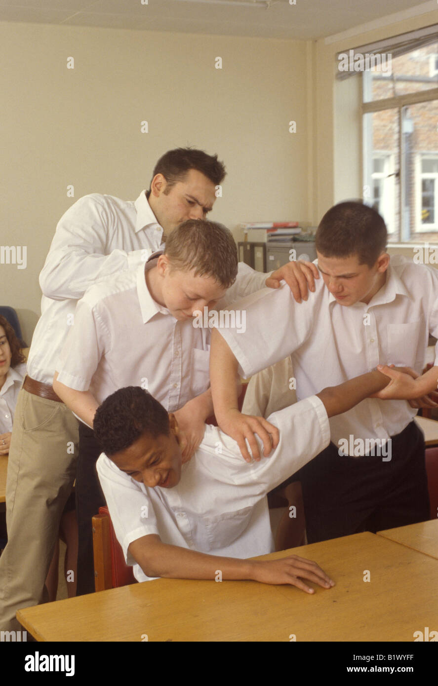 Lehrer, die Trennung von 3 Jungen kämpfen in der Klasse Stockfoto