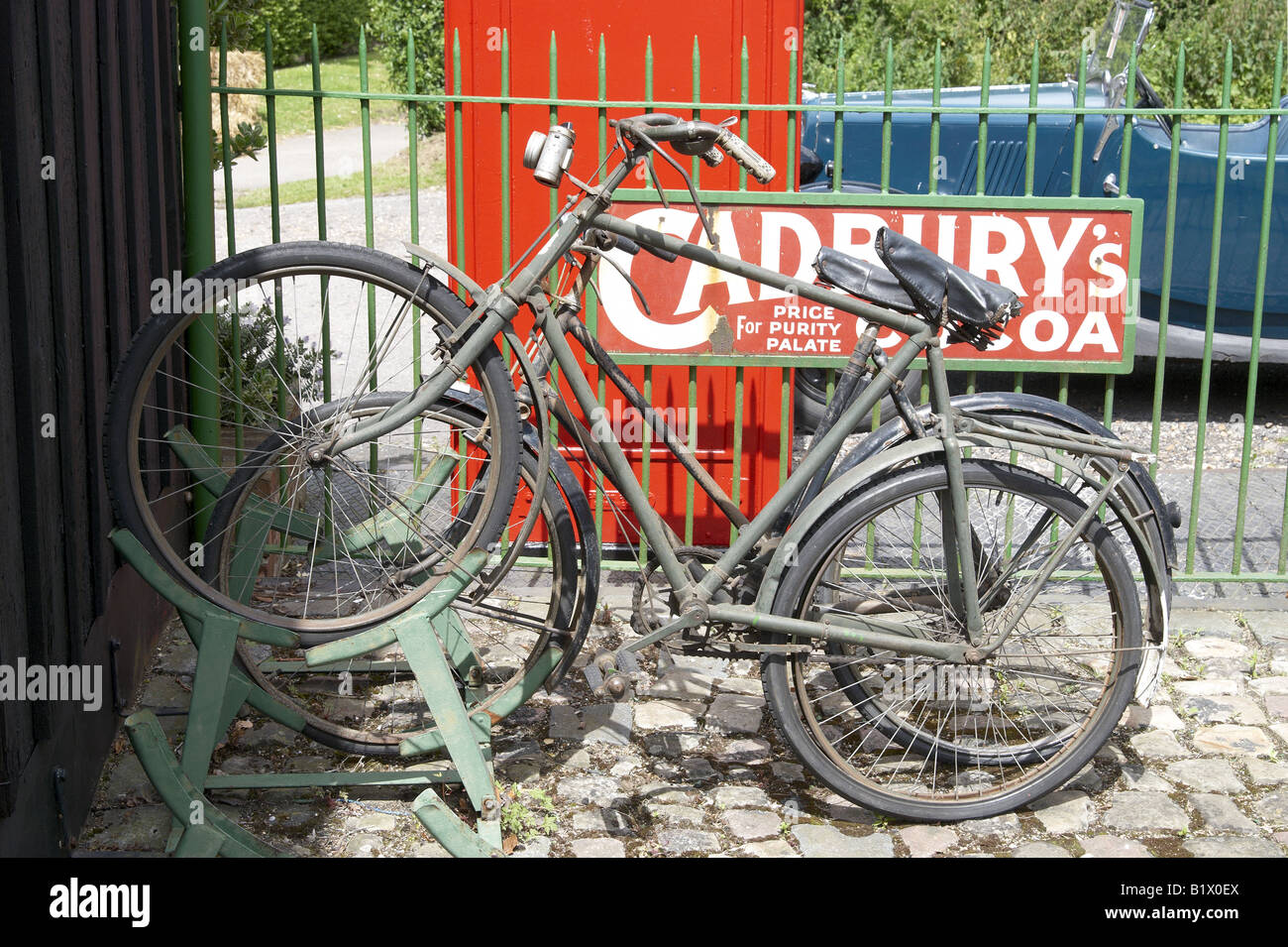 Altmodische Fahrräder in einem Fahrradständer auf dem erhaltenen Dampf Alter Bahnhof mit Werbung Emailleschild und rote Telefonzelle. Stockfoto