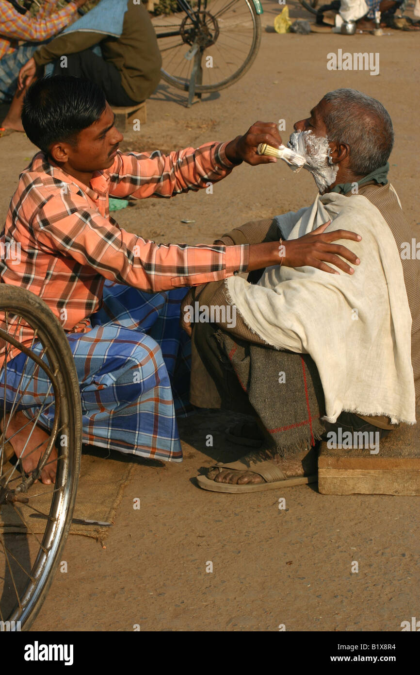 Barbier rasieren ein Kunde in den Straßen von Varanasi, Indien Stockfoto