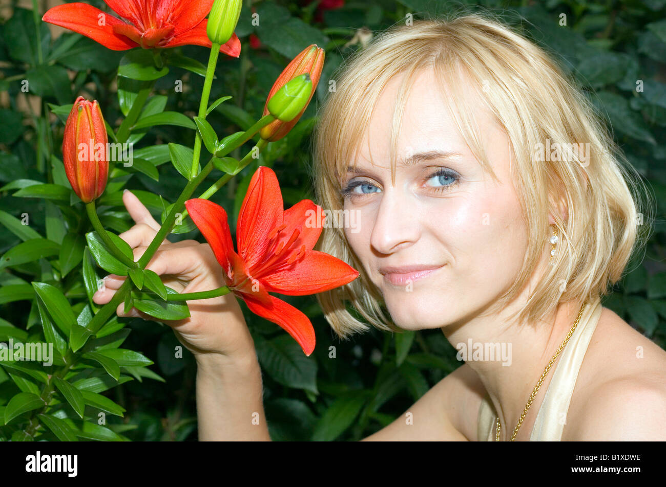 Porträt einer Frau im Garten durch den schönen roten Blüten. Stockfoto