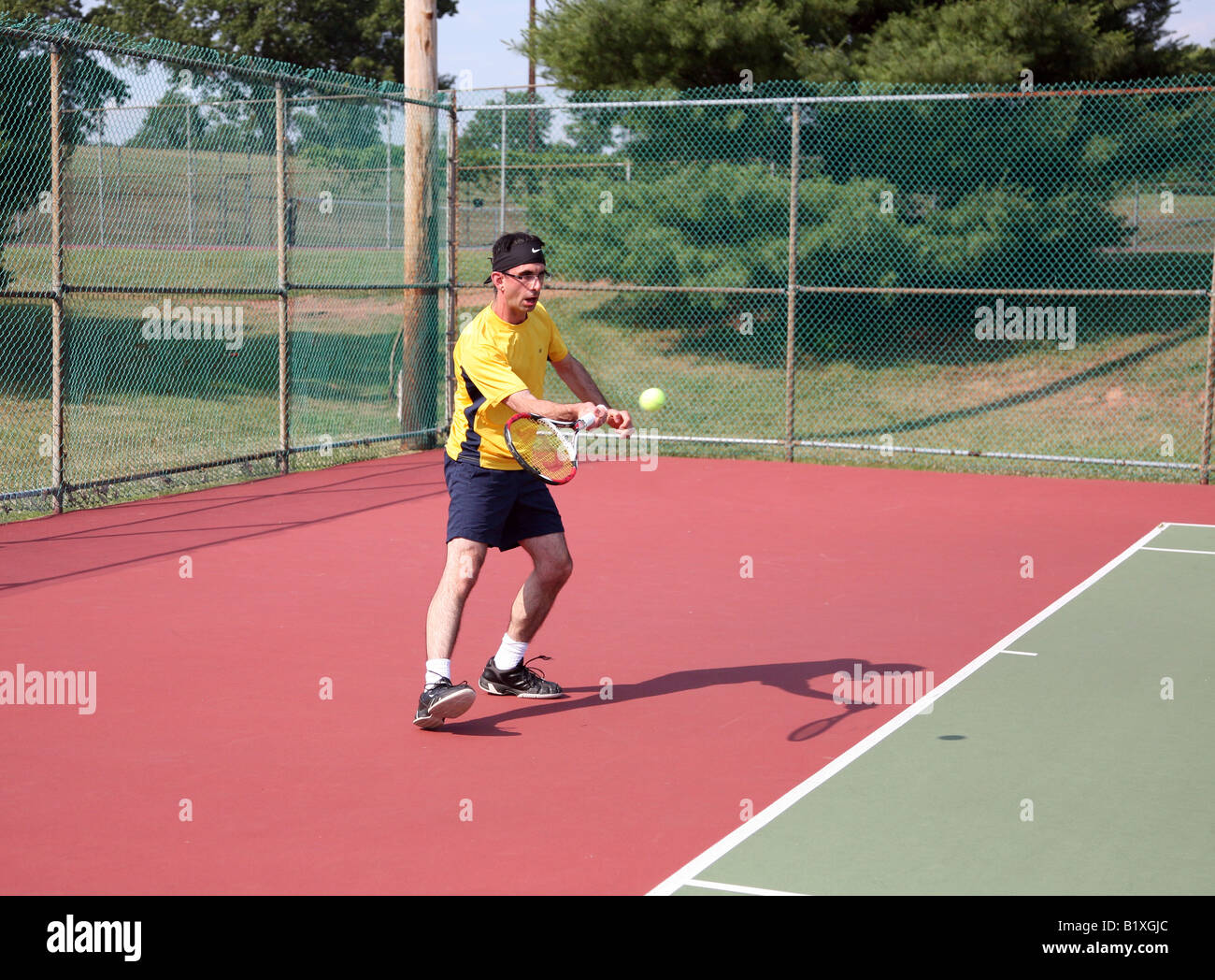 Ein junger Mann in einem gelben Hemd mit dem Tennisspielen. Stockfoto