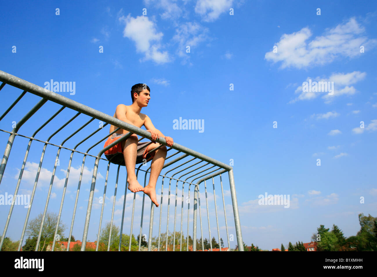 Teenager Jungen In Kurzen Hosen Sitzen Auf Ein Metall Tor Stockfotografie Alamy