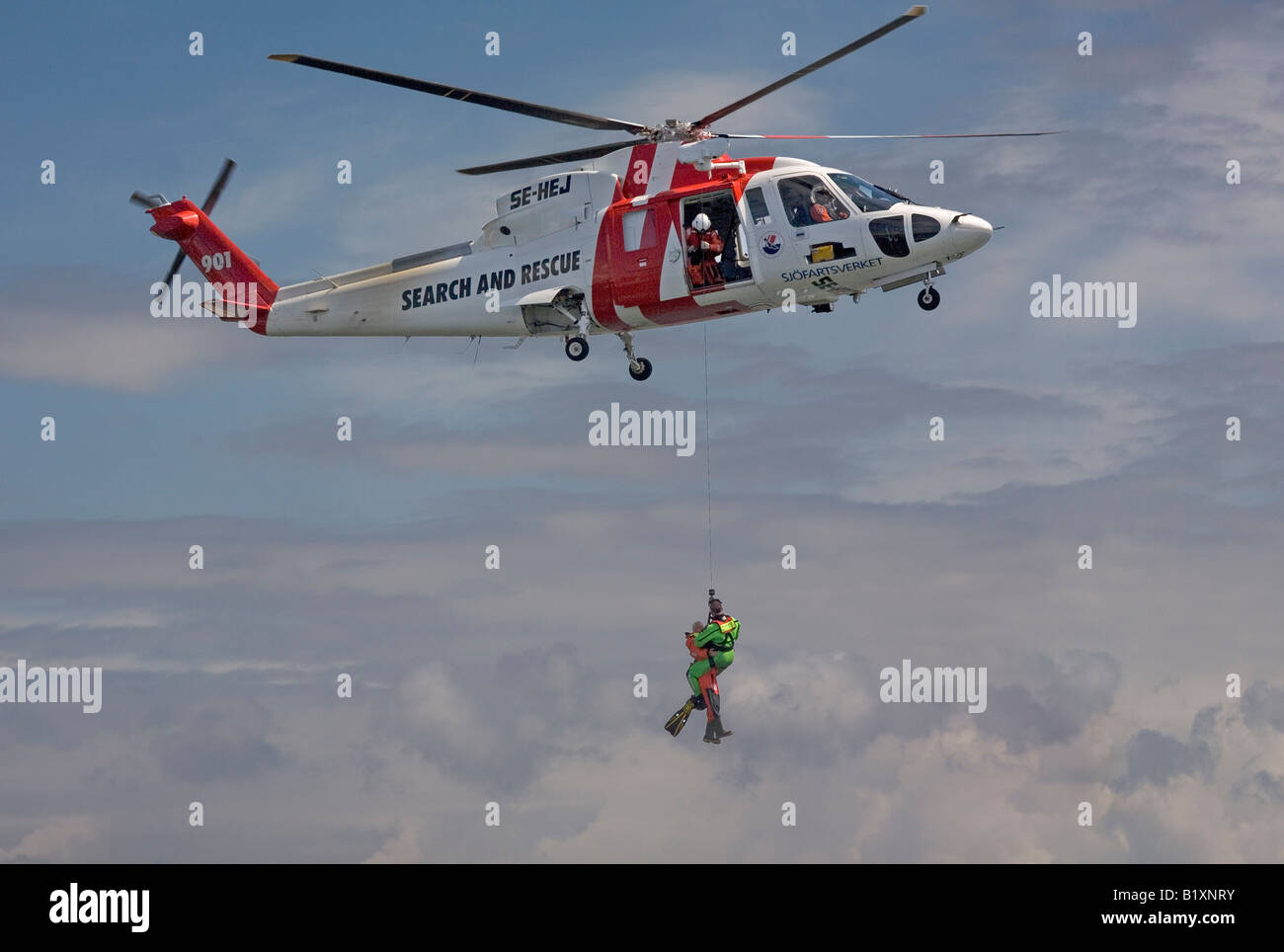 Such- und Rettungsdienst SAR-Hubschrauber-Team hisst eine Person mit Hilfe der Rettungsschwimmer Stockfoto