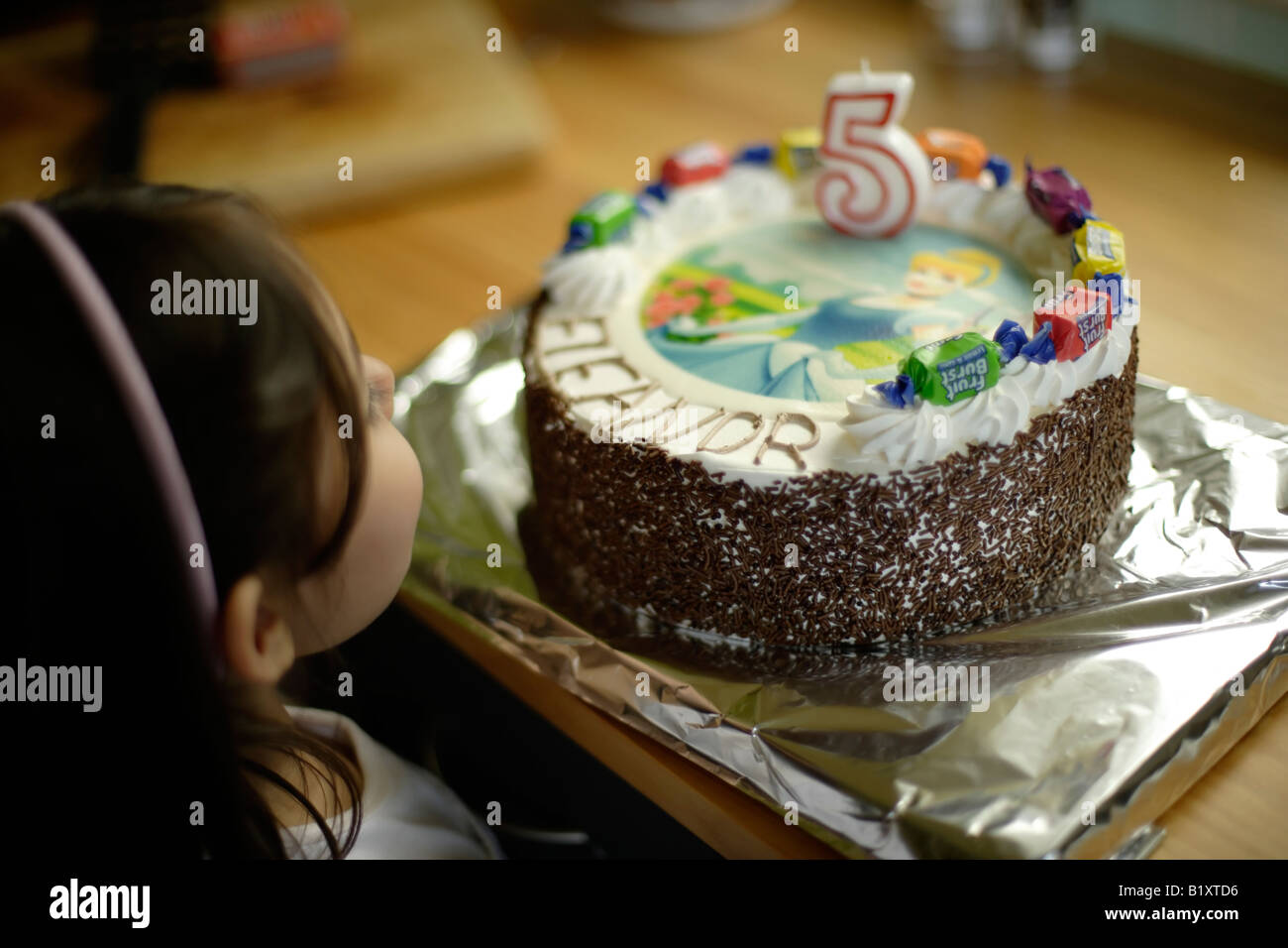Eleanor schaut ihr Geburtstagskuchen, bevor es an ihrem fünften Geburtstag serviert wird Stockfoto