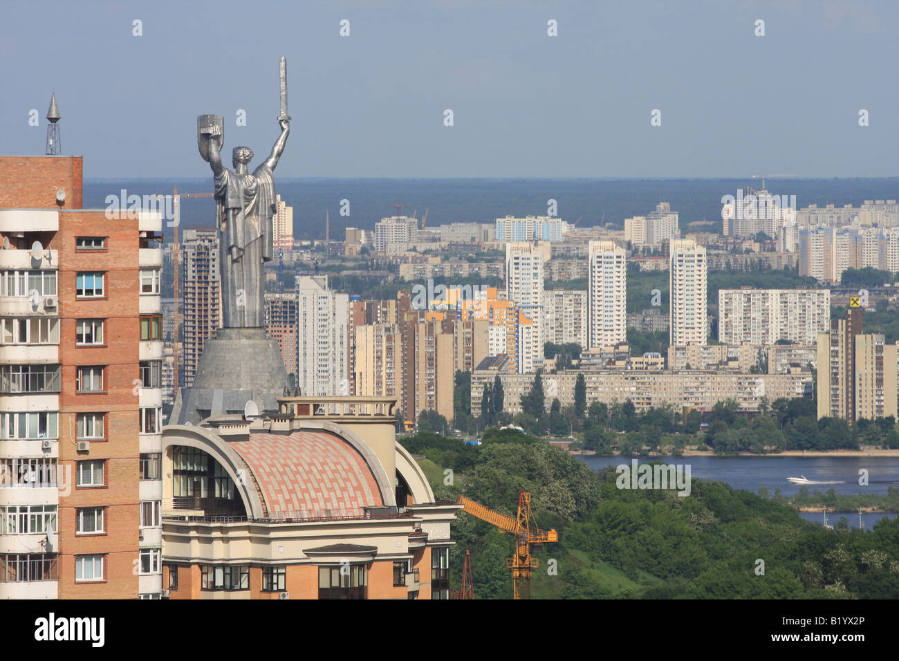 Das Mutterland-Denkmal in Kiew mit einer Skyline der Stadt im Hintergrund, mit modernen Hochhäusern und dem Fluss Dnipro. Stockfoto