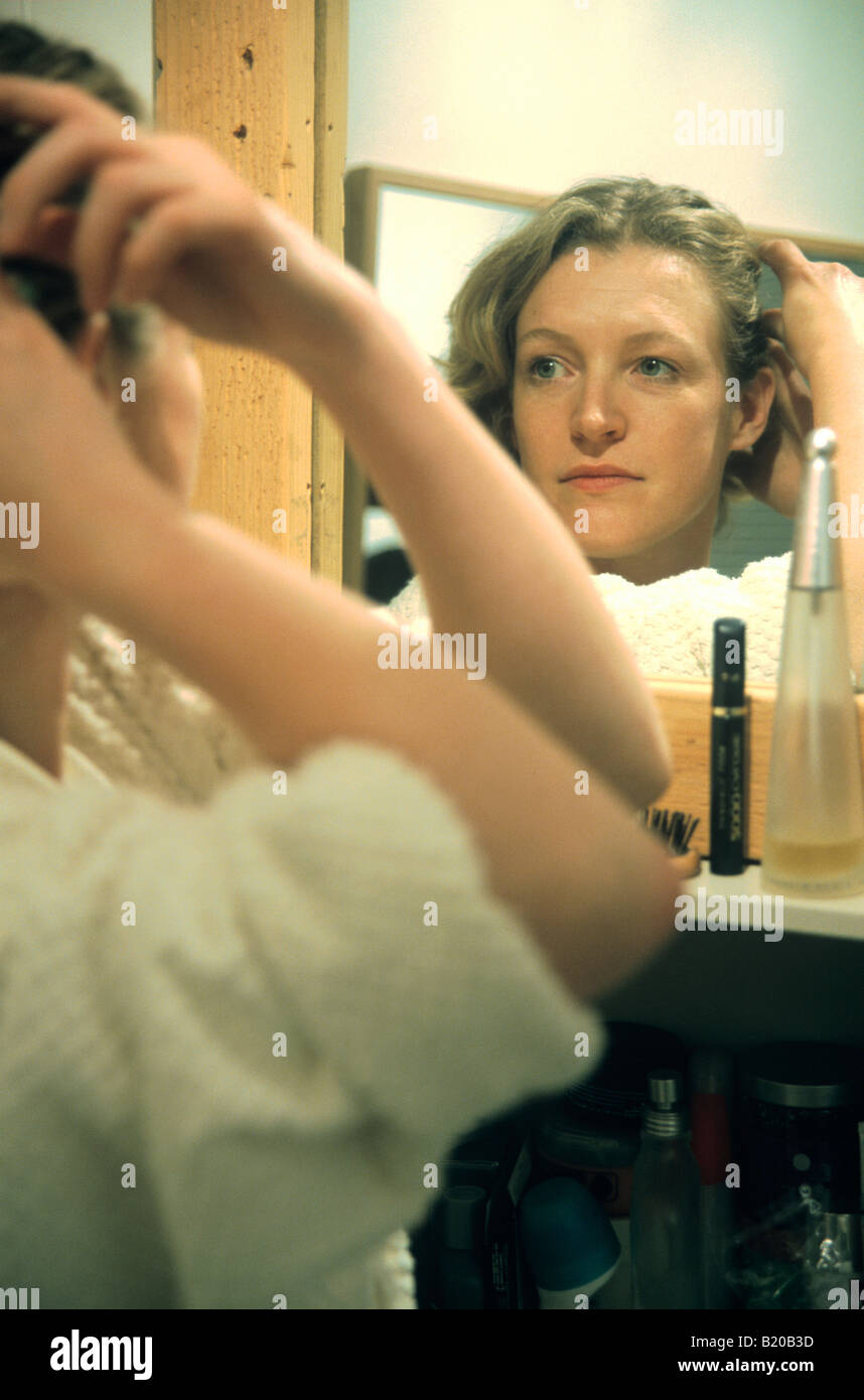 Frau macht ihr Haar im Spiegel Stockfoto