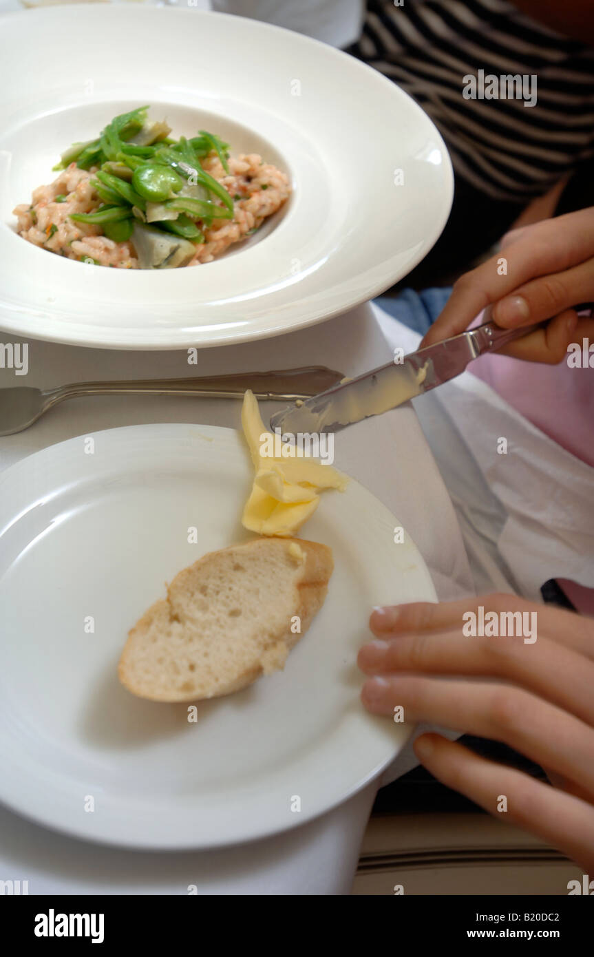 EINE PORTION RISOTTO ZUM MITTAGESSEN IN EINEM RESTAURANT MIT EINEM STÜCK BAGUETTE MIT BUTTER AUF EINER SEITE PLATTE UK Stockfoto