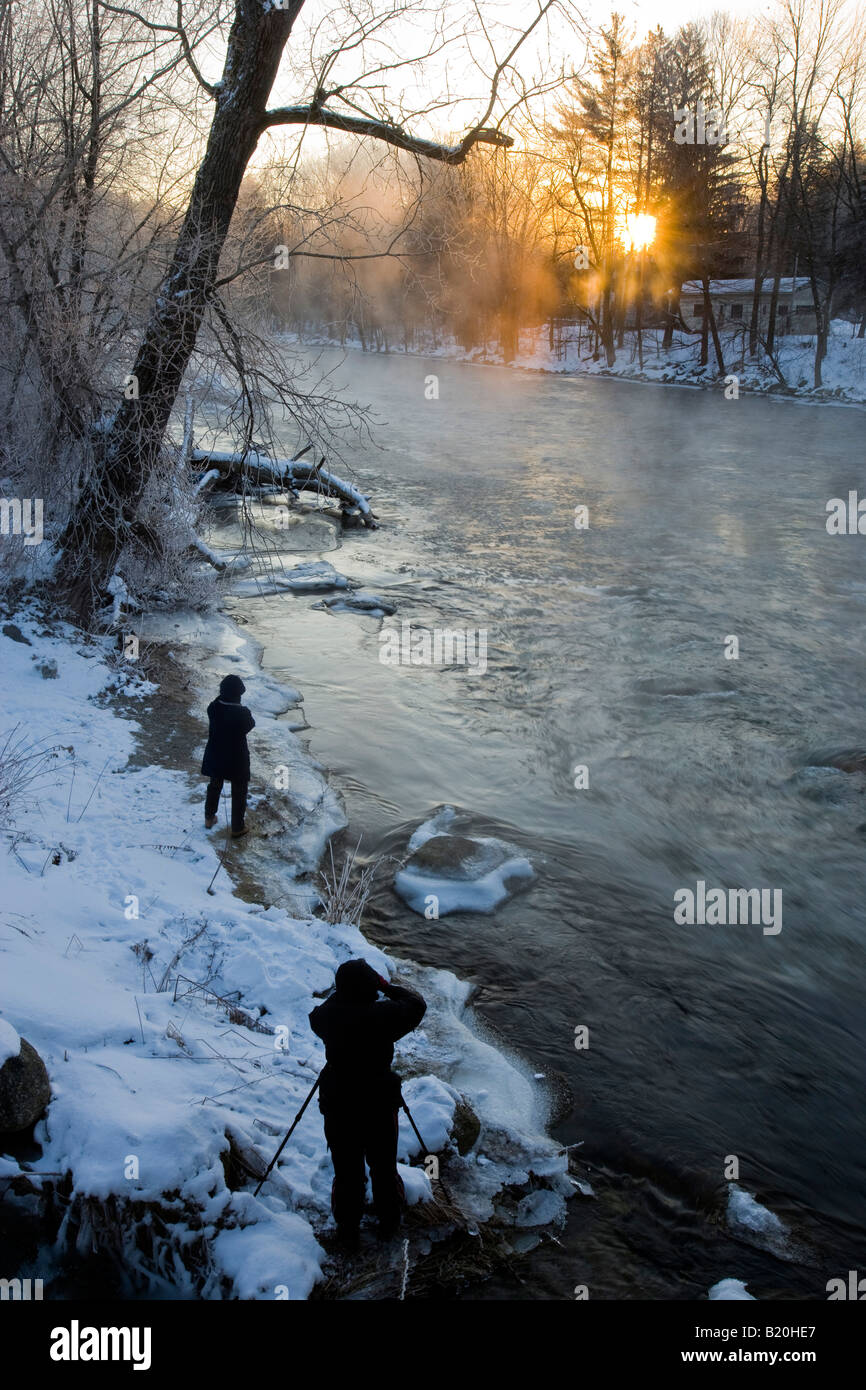 Fotografen fotografieren einen Winter-Sonnenaufgang über den Ashuelot River in Winchester, New Hampshire. Stockfoto