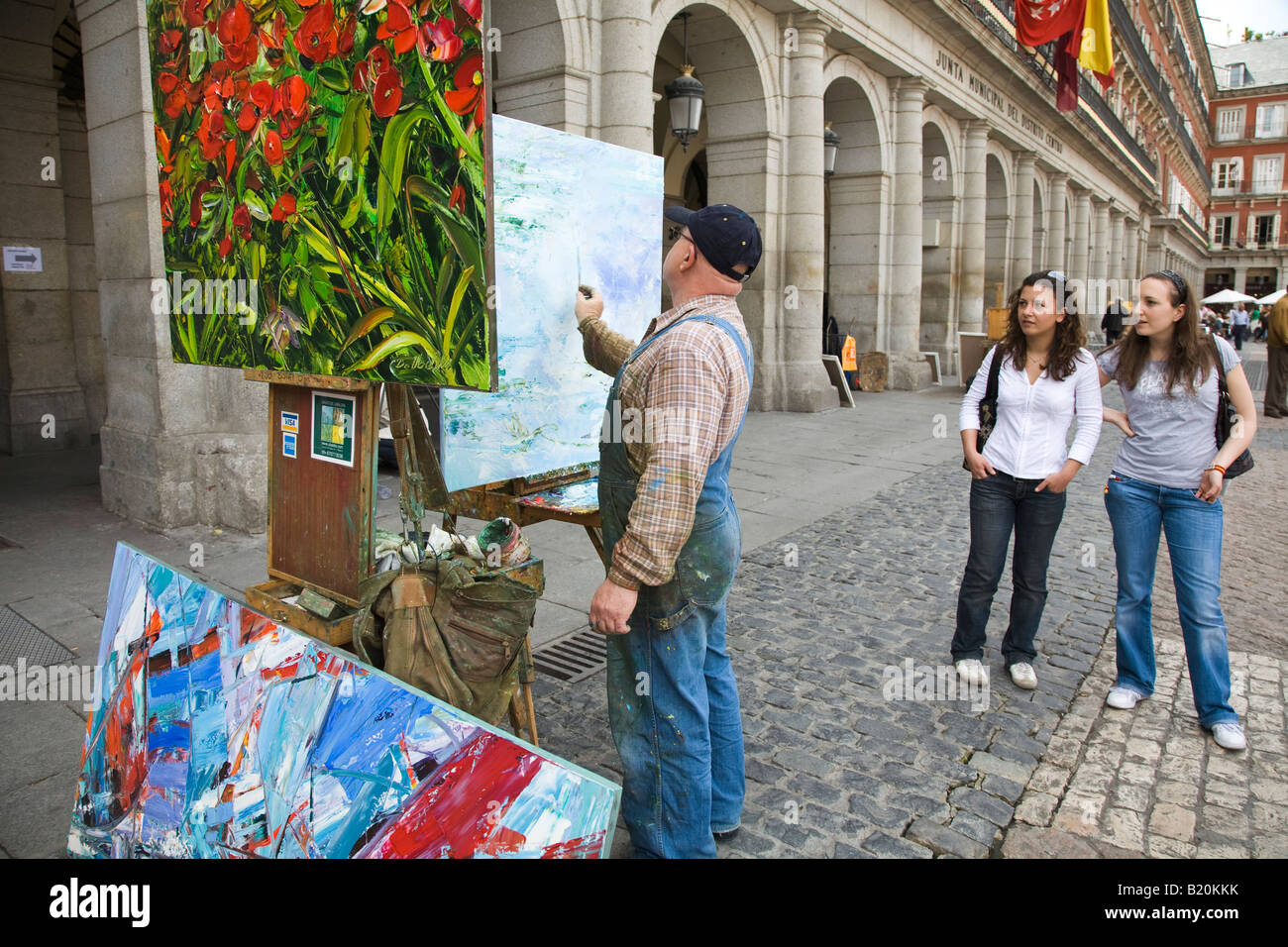 Spanien Madrid Mann malen auf Leinwand in der Plaza Mayor abgeschlossen Malerei von roten Mohnblumen auf Staffelei zwei Mädchen gerade Mann arbeiten Stockfoto