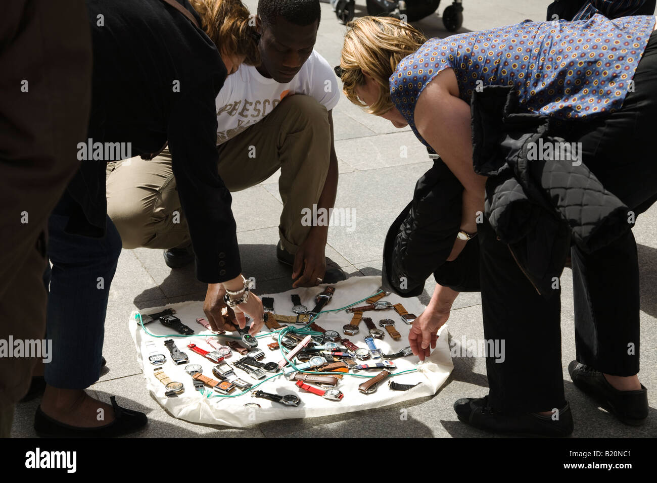 Spanien Madrid zwei Frau betrachten Uhren zum Verkauf von Straßenhändler, die Ware auf Tuch auf dem Bürgersteig angezeigt Stockfoto