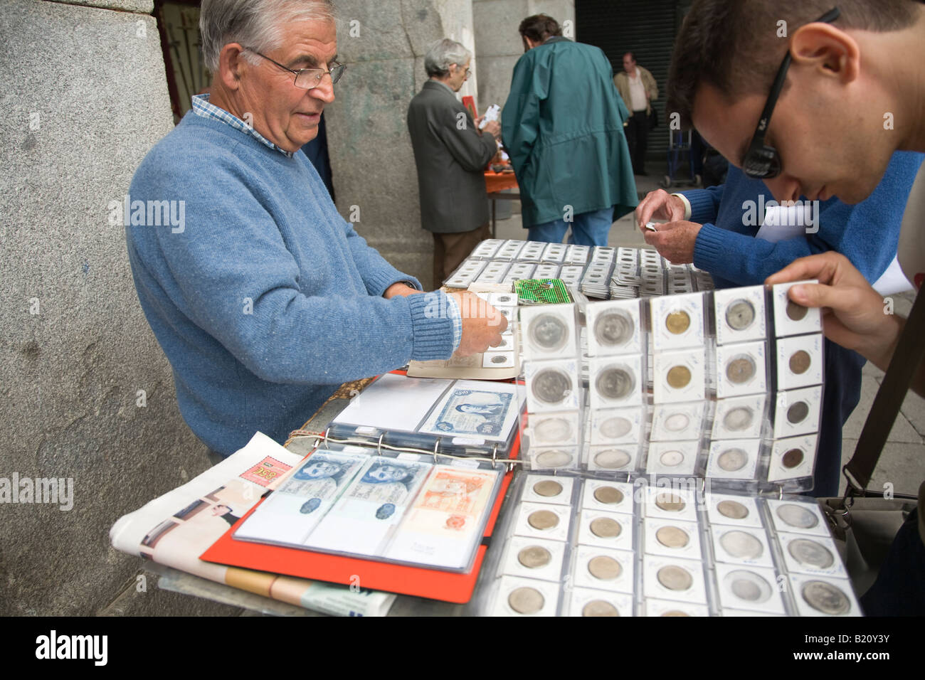 Spanien Madrid erwachsenen Mannes anzeigen Münze und Währung Sammlung zum Verkauf in Plaza Mayor am Sonntagmorgen Sammler suchen notebooks Stockfoto