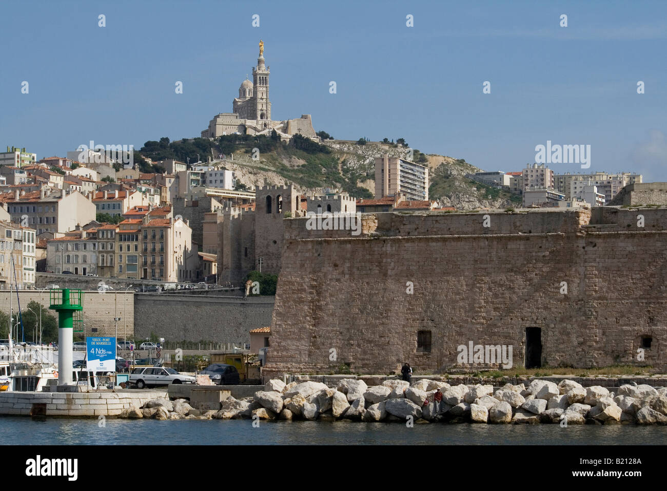 Blick auf Marseille Hafen Blick von der Hafeneinfahrt zurück in Richtung Kathedrale Notre Dame De La Garde auf dem Hügel. Stockfoto