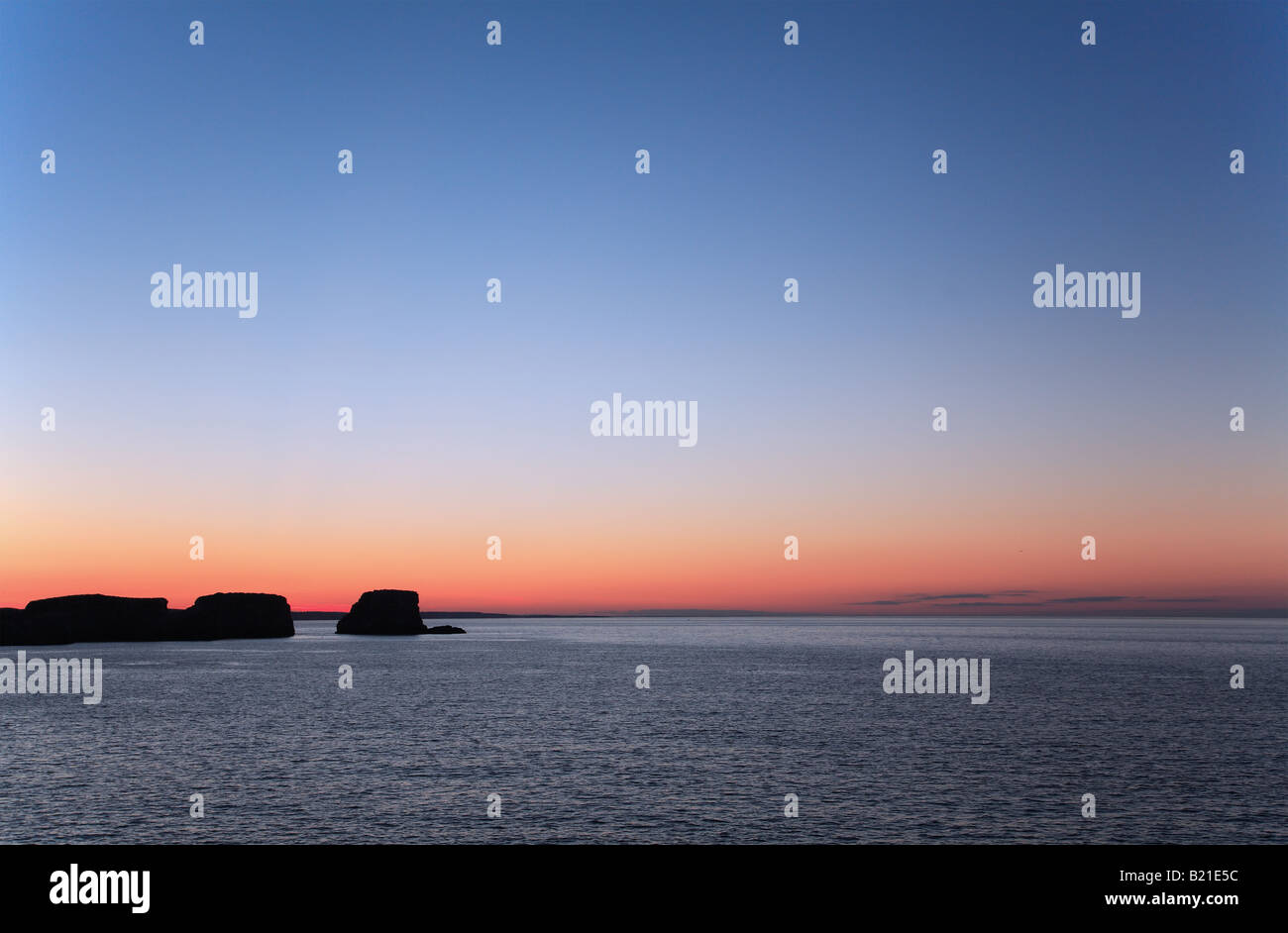 Eine Orange Leuchten Sonnenuntergang über dem Meer mit Silhoutted Felsformationen in Sagres, Algarve, Portugal Stockfoto