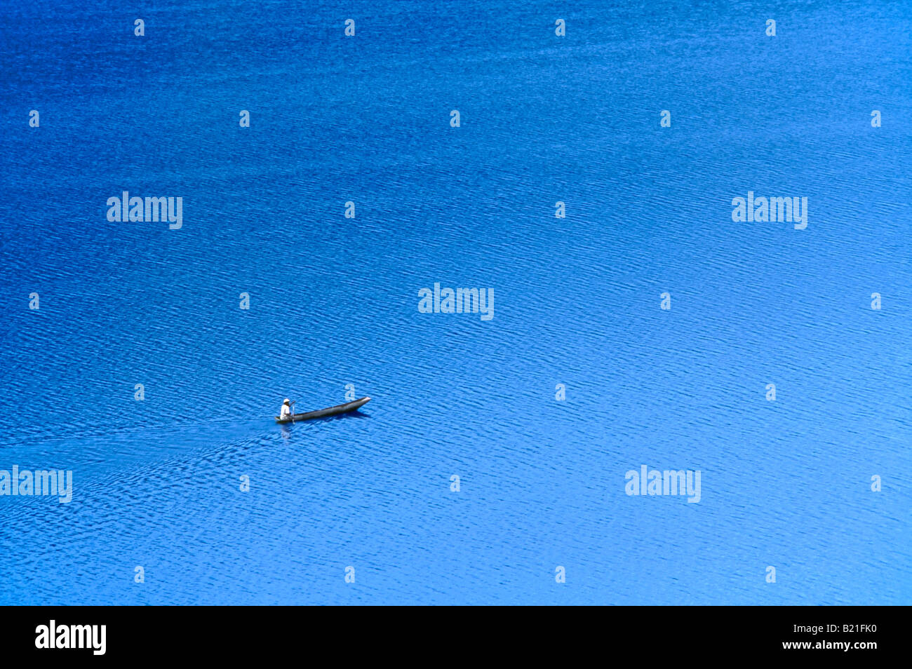 Ein einsamer einsame Mann in einem hölzernen Einbaum Kanu Springer-über Lake Bunyonyi. Stockfoto