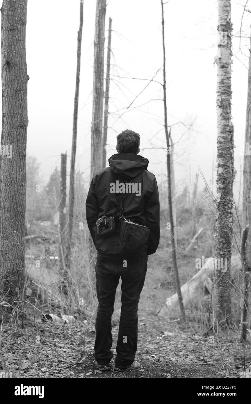 Ein Mann, eine Kamera zu Fuß durch eine klare Wald im Regen. Stockfoto