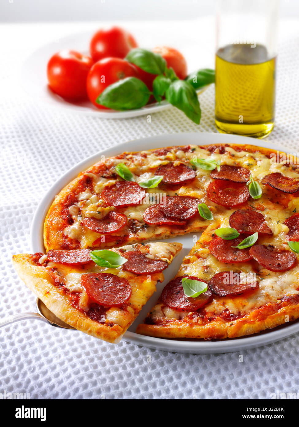 Pizza mit Salami, Basilikum mit einer Scheibe aus Stockfoto