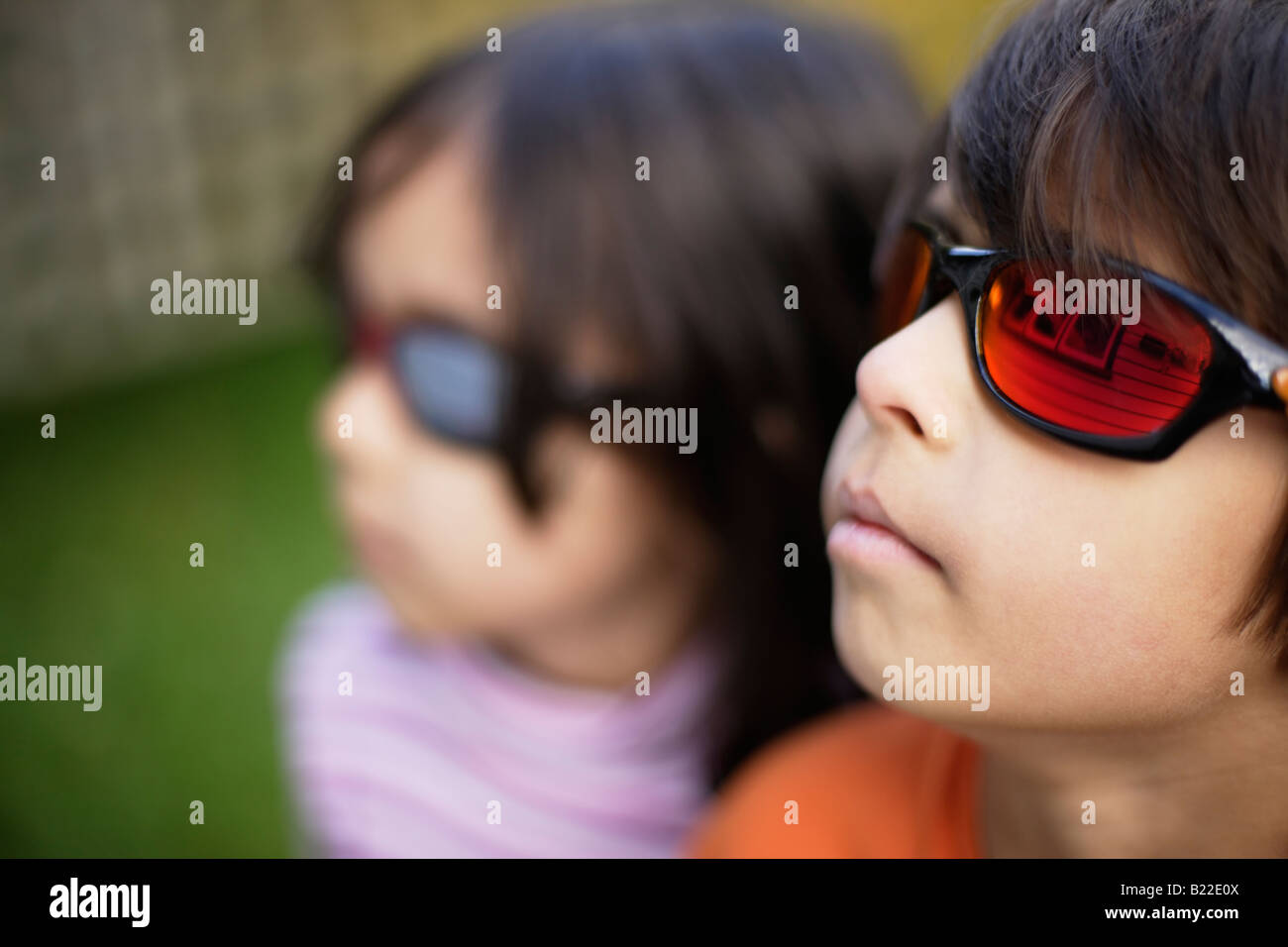 Junge im Alter von sechs und tragen Schwester vier verspiegelte Sonnenbrillen außen Wetterschenkel nach Hause und Fenster in Objektiv widerspiegeln Stockfoto