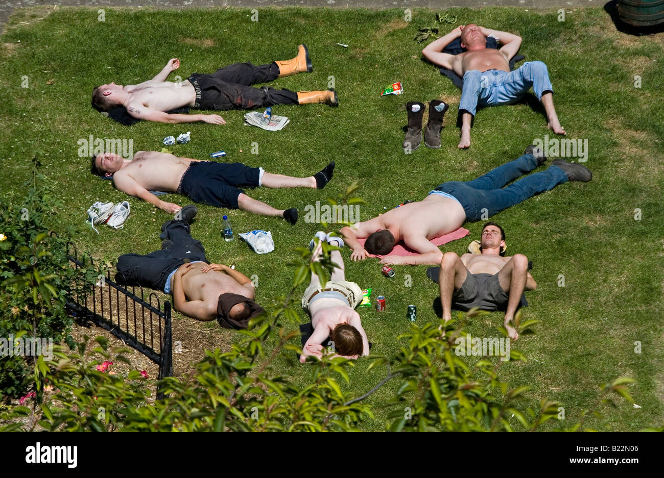 Gruppe junger Arbeitnehmer ruht auf dem Rasen an einem heißen Sommertag in der Mittagspause London England UK Stockfoto