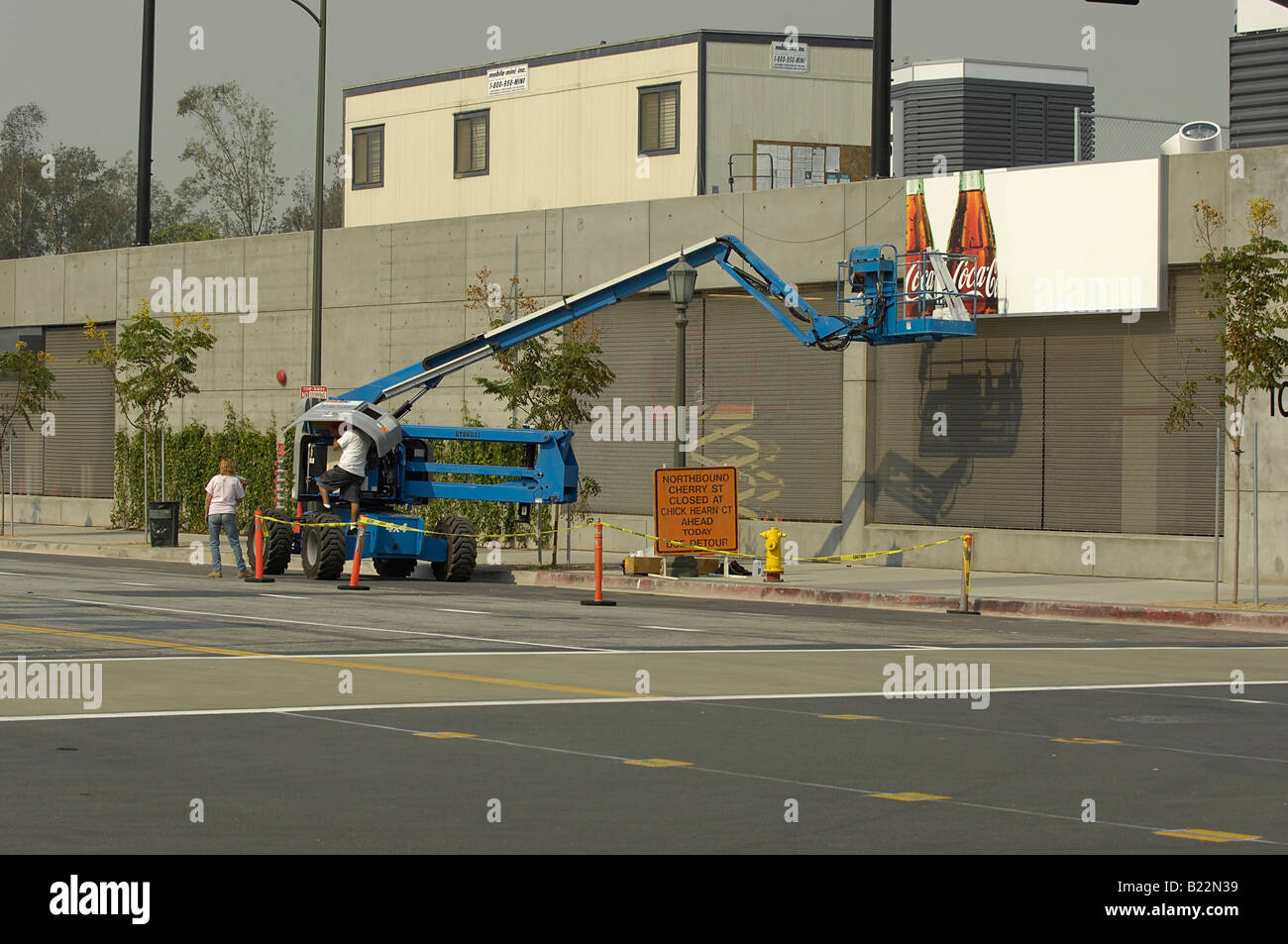 Arbeitnehmer mit einer Hubarbeitsbühne Typ Kran um Aufmachungen eine Plakatwand nehmen eine Auszeit um Kraftstoff und Wartung auf ihre Ausrüstung zu tun. Stockfoto