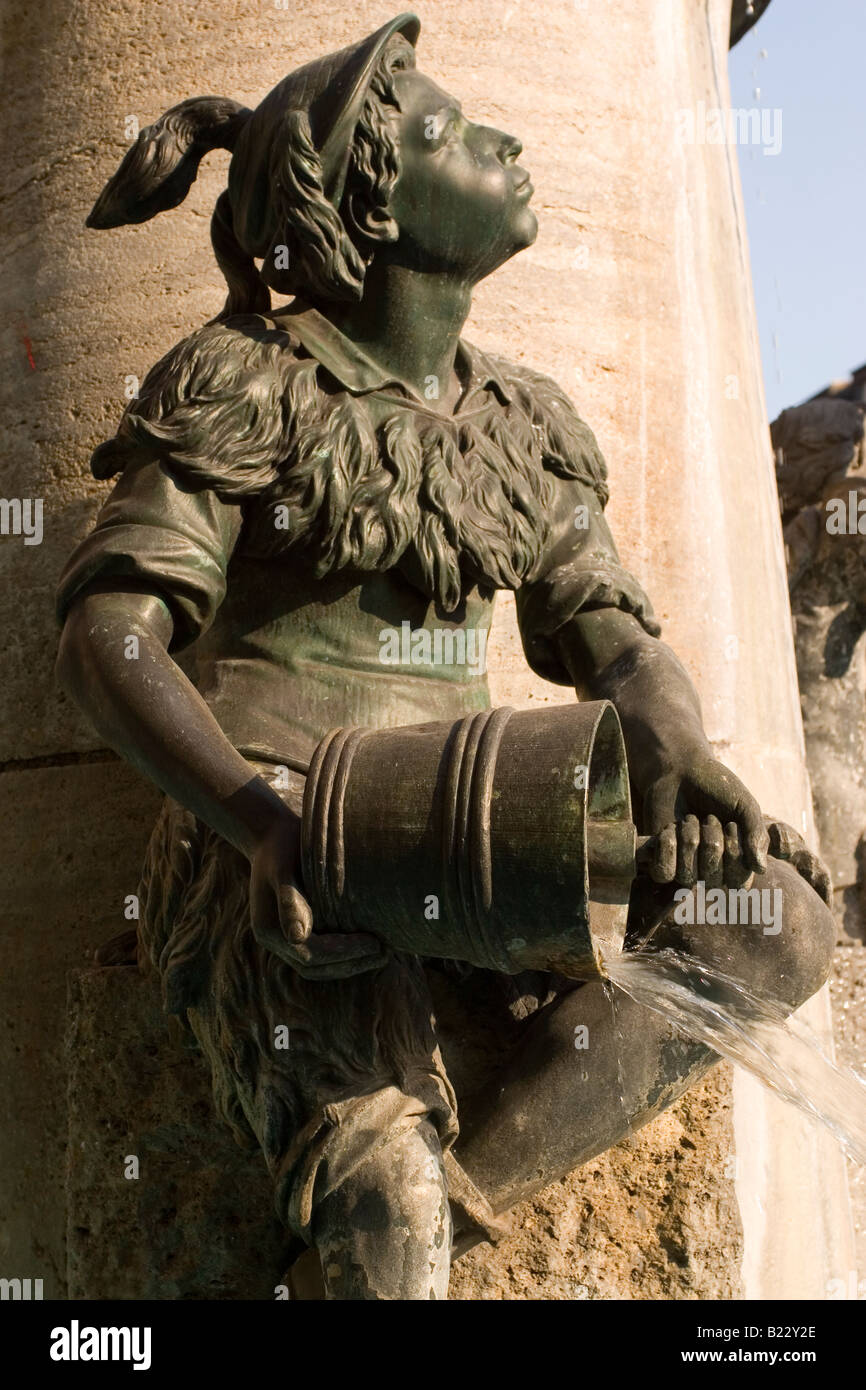 Wasser strömt aus einem Eimer auf einer Statue in München. Die Figur ist Teil der Fischbrunnen auf dem Marienplatz. Stockfoto