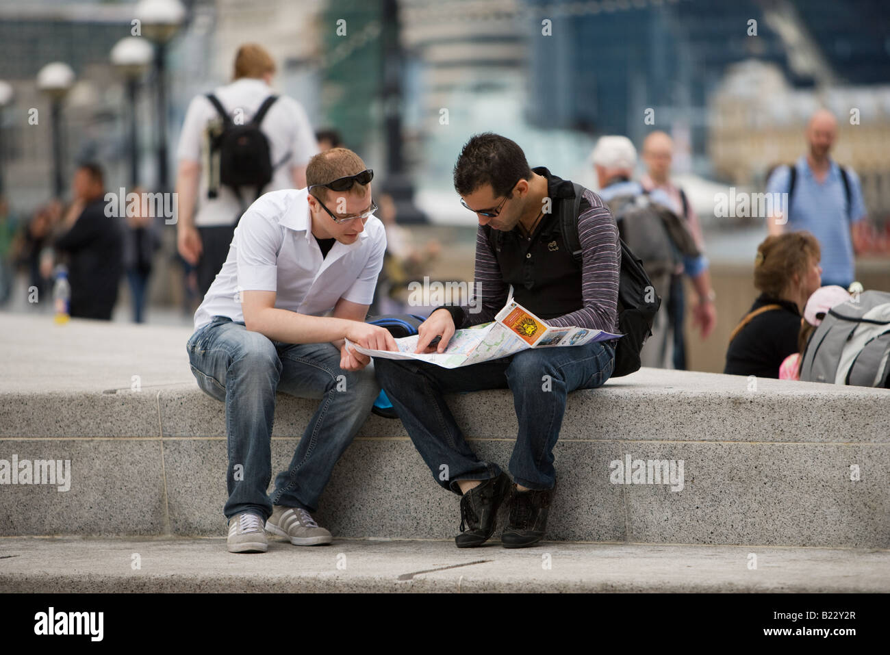 Zwei junge Männer, Touristen, die eine Karte und Reiseführer Buch am Südufer in der Nähe von City Hall, London Stockfoto