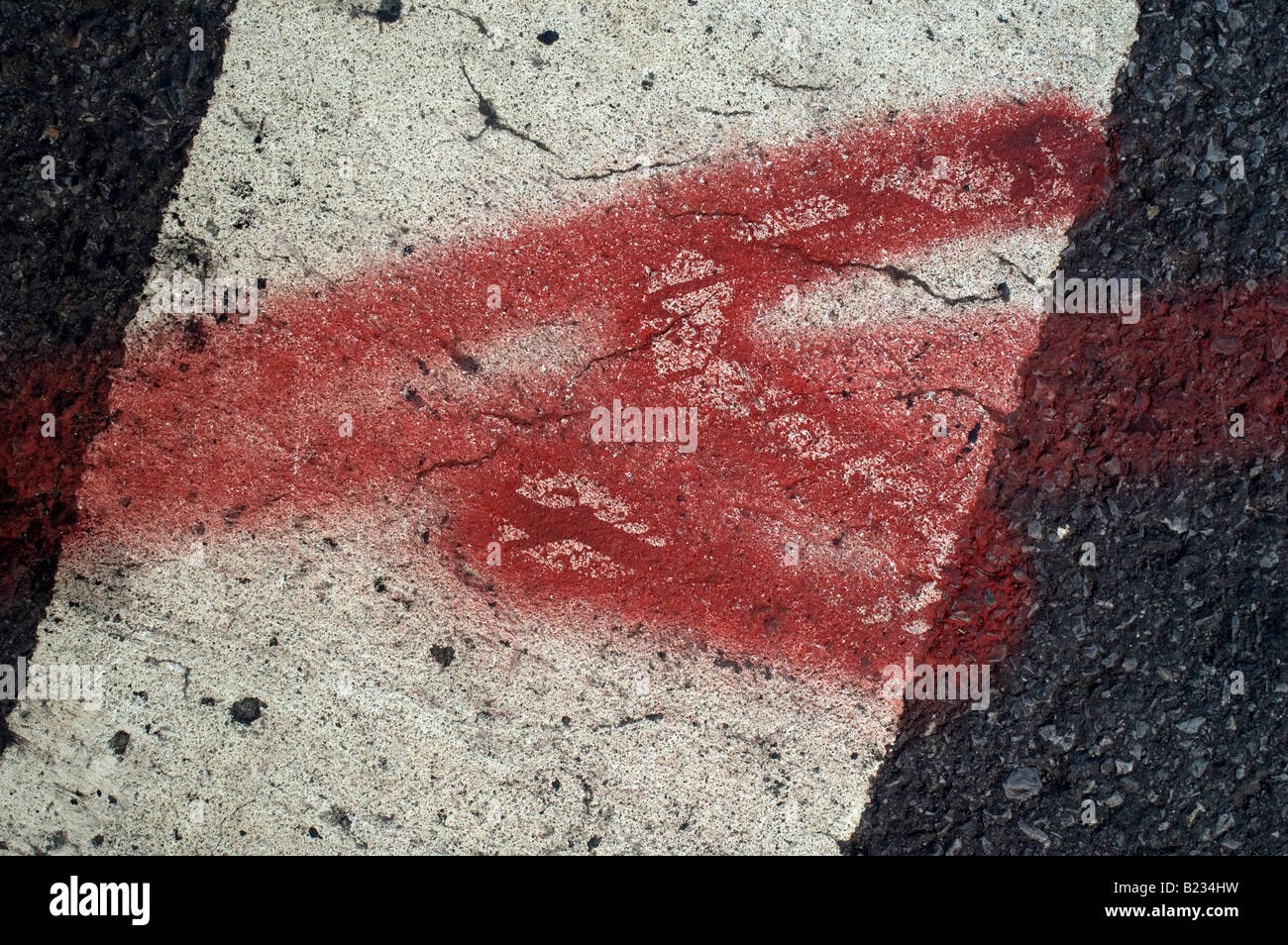 Nahaufnahme von gemalten roten Pfeil auf eine weiße Fahrbahnmarkierung auf ein Konglomerat konkrete Straße Stockfoto