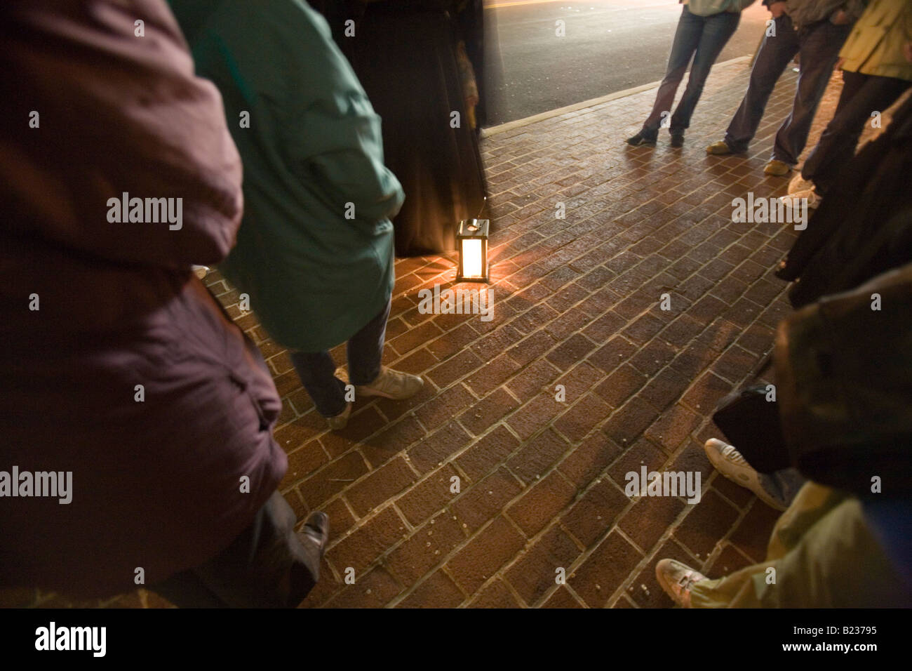 Touristen stehen in einem Kreis um eine Laterne und Geistergeschichten anhören Stockfoto