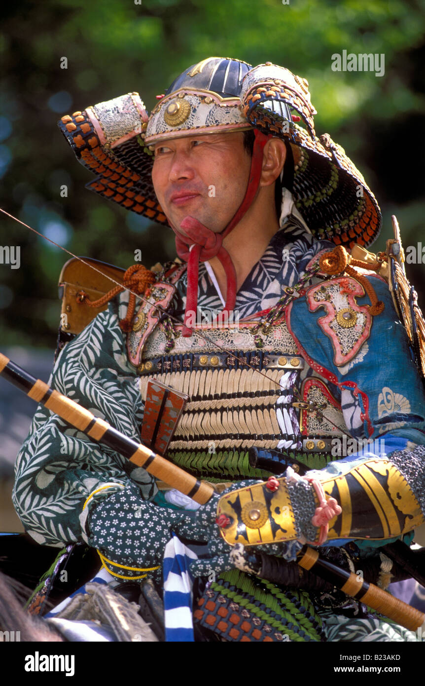 Samurai-Krieger Rüstung und einen Helm tragen hält einen Bogen Bogenschießen und Reiten Stockfoto