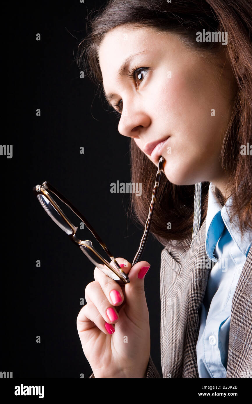 Nachdenklich Geschäftsfrau mit Brille auf dunklem Hintergrund Stockfoto