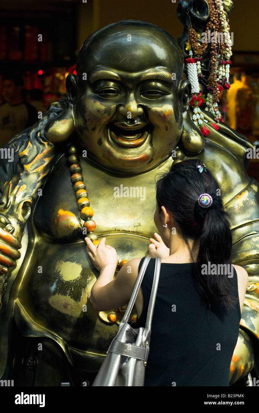 Chinesische Frau betet ein lächelnder Buddha in Singapur Stockfoto