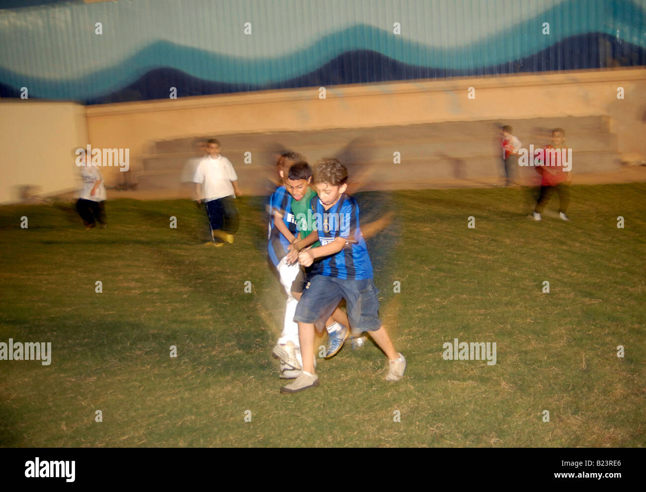 Saudische Schule Kinder spielen Fußball auf einem künstlichen Rasen am Abend zu vermeiden, die Wärme, Jeddah, Saudi Arabien Stockfoto