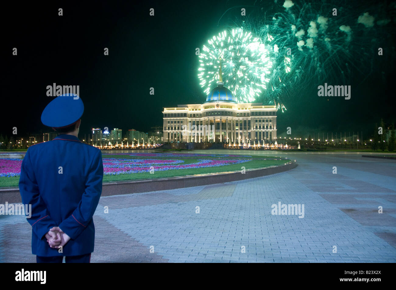 Ein Polizist beobachtet Feuerwerk über Ak Orda Residenz des Präsidenten der Republik Kasachstan, in Astana, Kasachstan Stockfoto