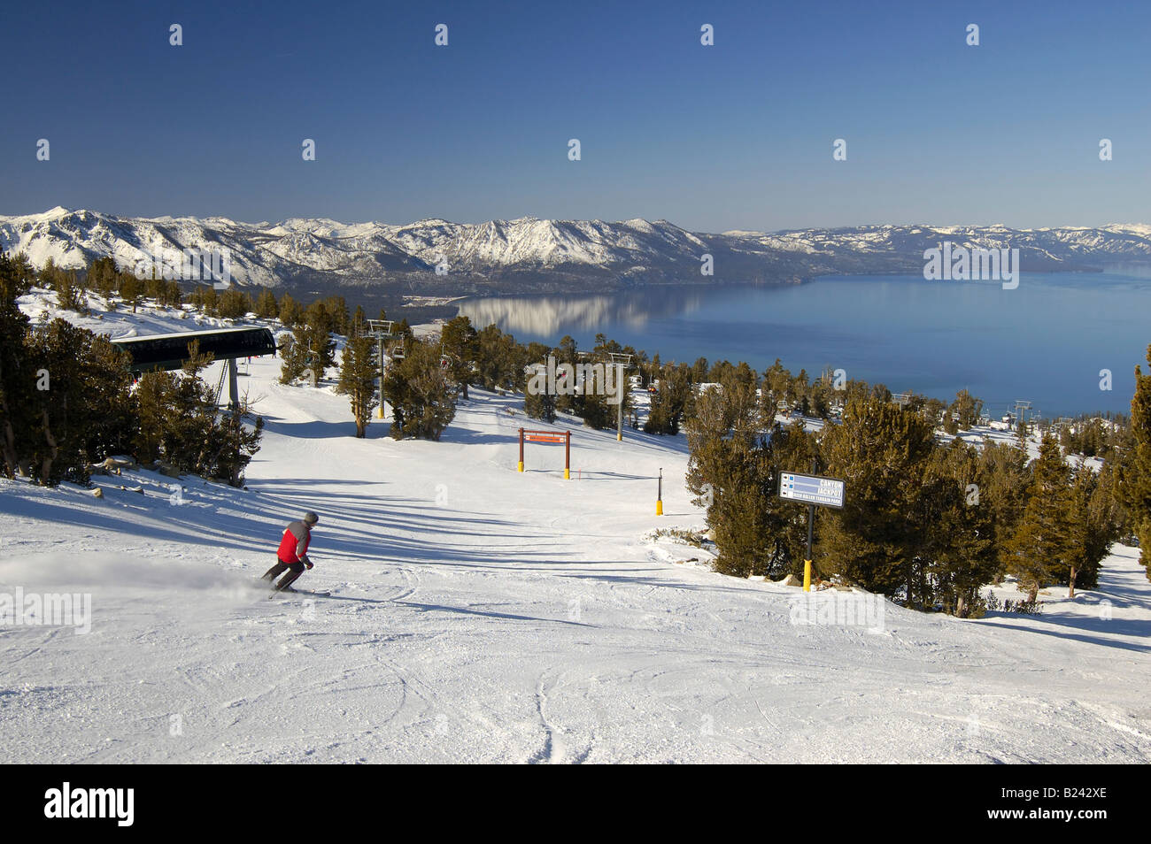 Skipiste am Lake Tahoe Resort mit dem See im Hintergrund und ein wenig Bewegung verwischt Skifahrer im Vordergrund Stockfoto