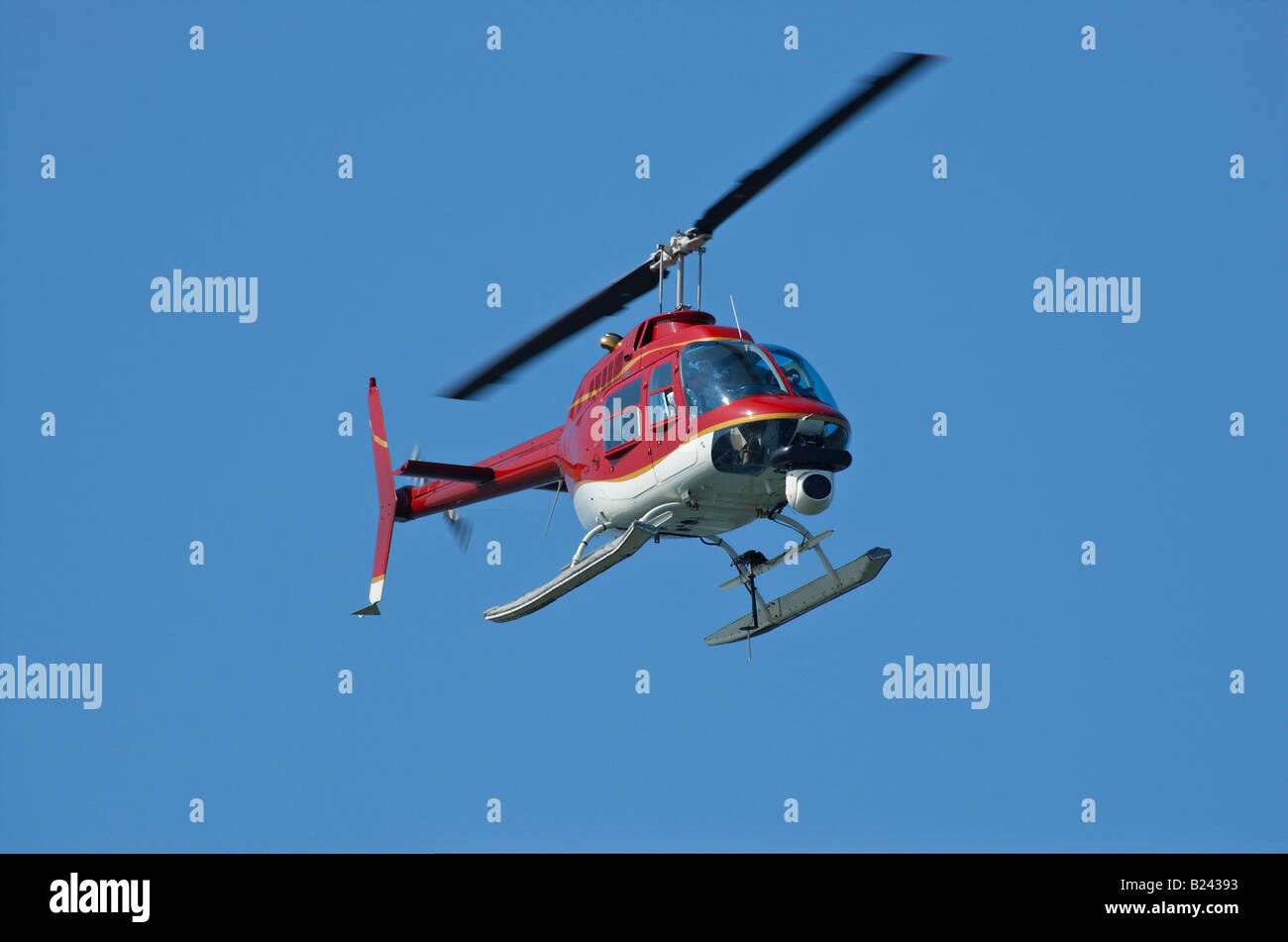 Eine helle rote Hubschrauber mit einer Kamera ein wenig Bewegungsunschärfe auf Rotorblätter Stockfoto