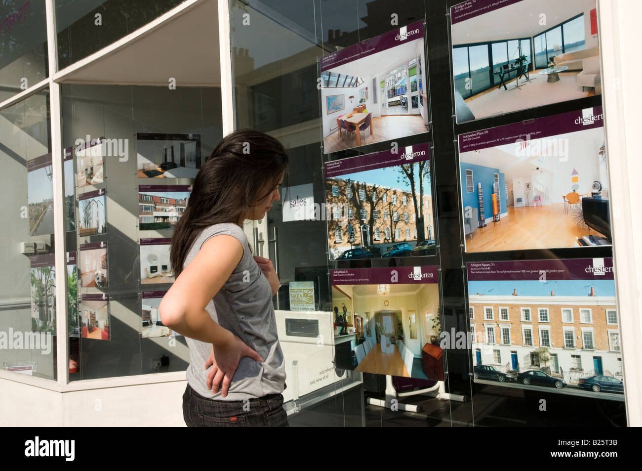 First time junge Käufer Blick auf teure Häuser zum Verkauf in Immobilienmakler Fenster in London England UK Stockfoto